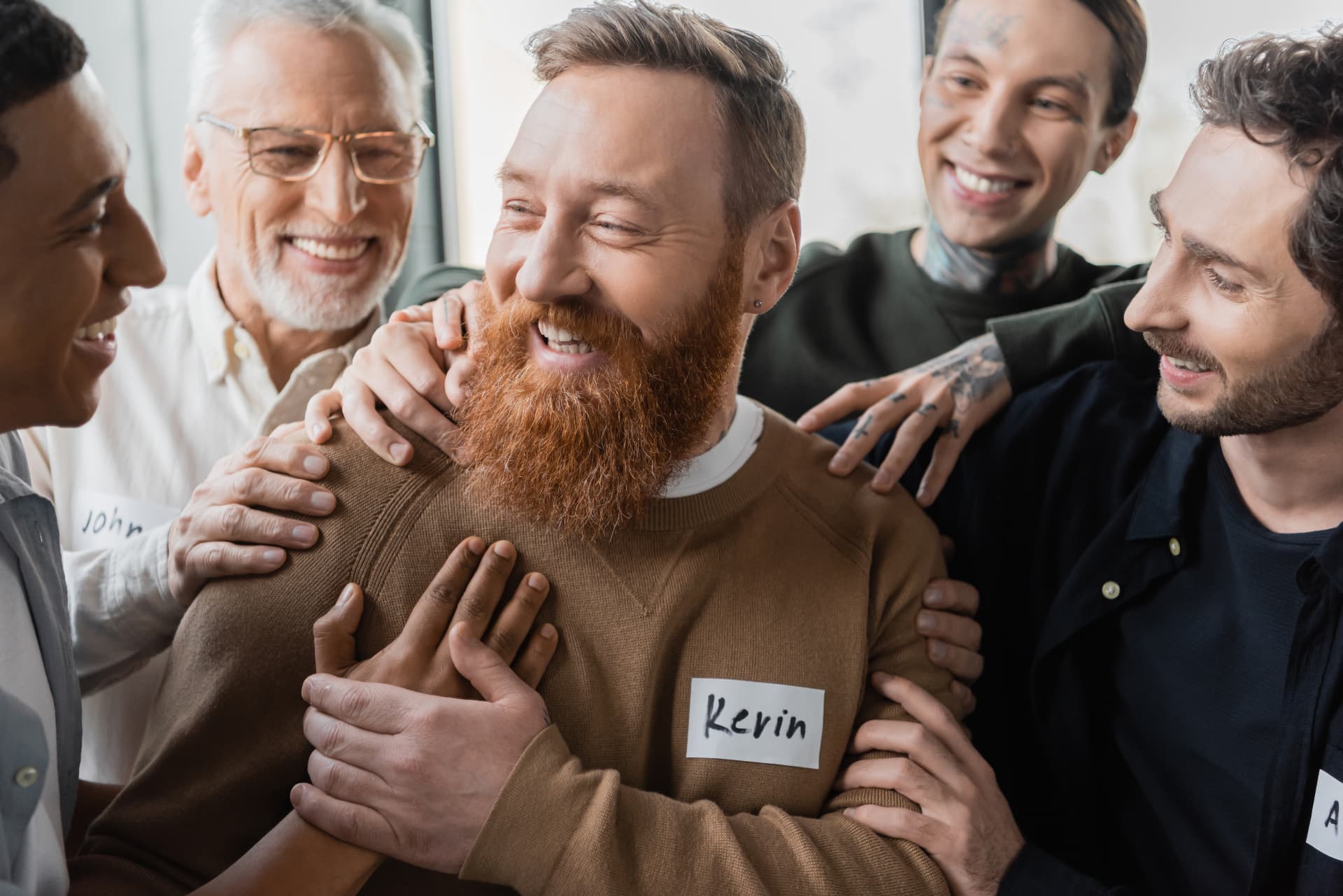 Men standing close together with hands on each other’s shoulders, laughing
