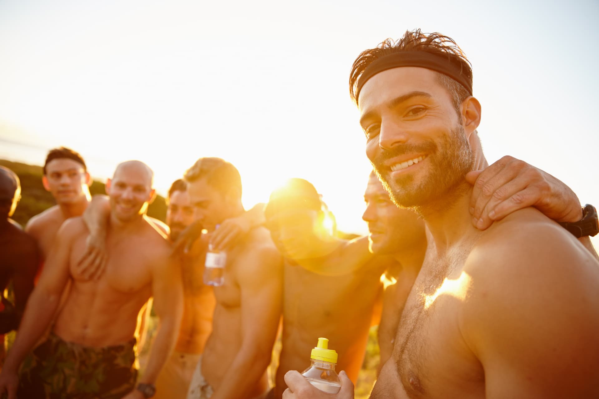 Men standing arm in arm and smiling outdoors after a session