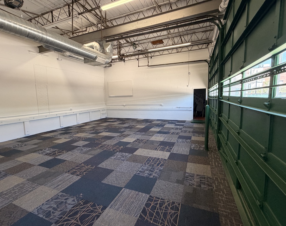 Open studio room with natural light and green garage-door windows